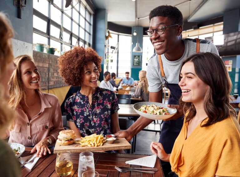 Three women being served lunch by a man at a restaurant