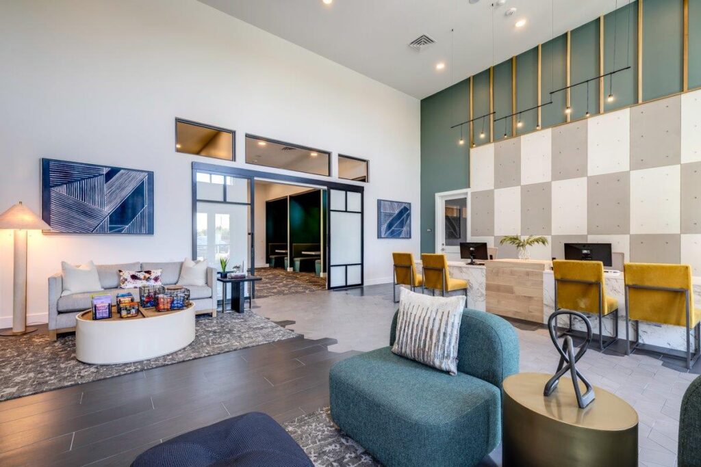 Modern apartment community space with seating area and a reception desk.
