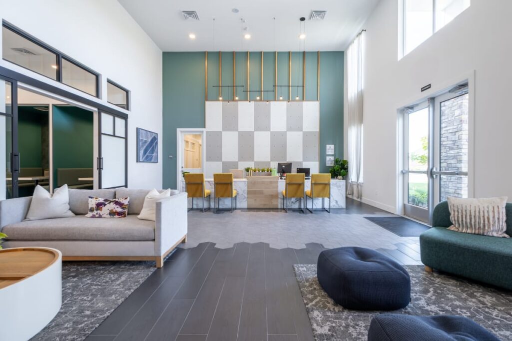 A modern community space with sofas, poufs, and a communal table with yellow chairs.
