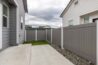 Outdoor view of an apartment's fenced patio area with a concrete surface and small patch of artificial grass.