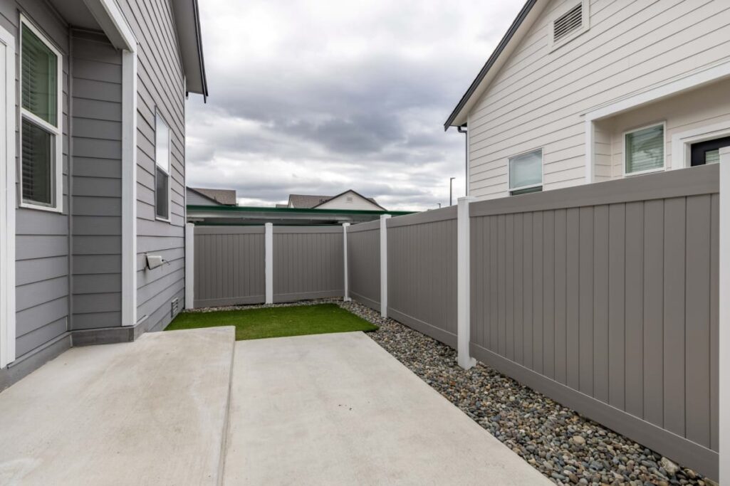 Outdoor view of an apartment's fenced patio area with a concrete surface and small patch of artificial grass.