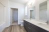 Modern bathroom in an apartment featuring a double-sink vanity, large mirror, toilet, and bright lighting.