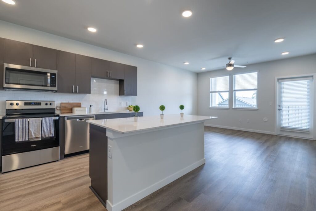 Modern apartment kitchen with stainless steel appliances and a central island.
