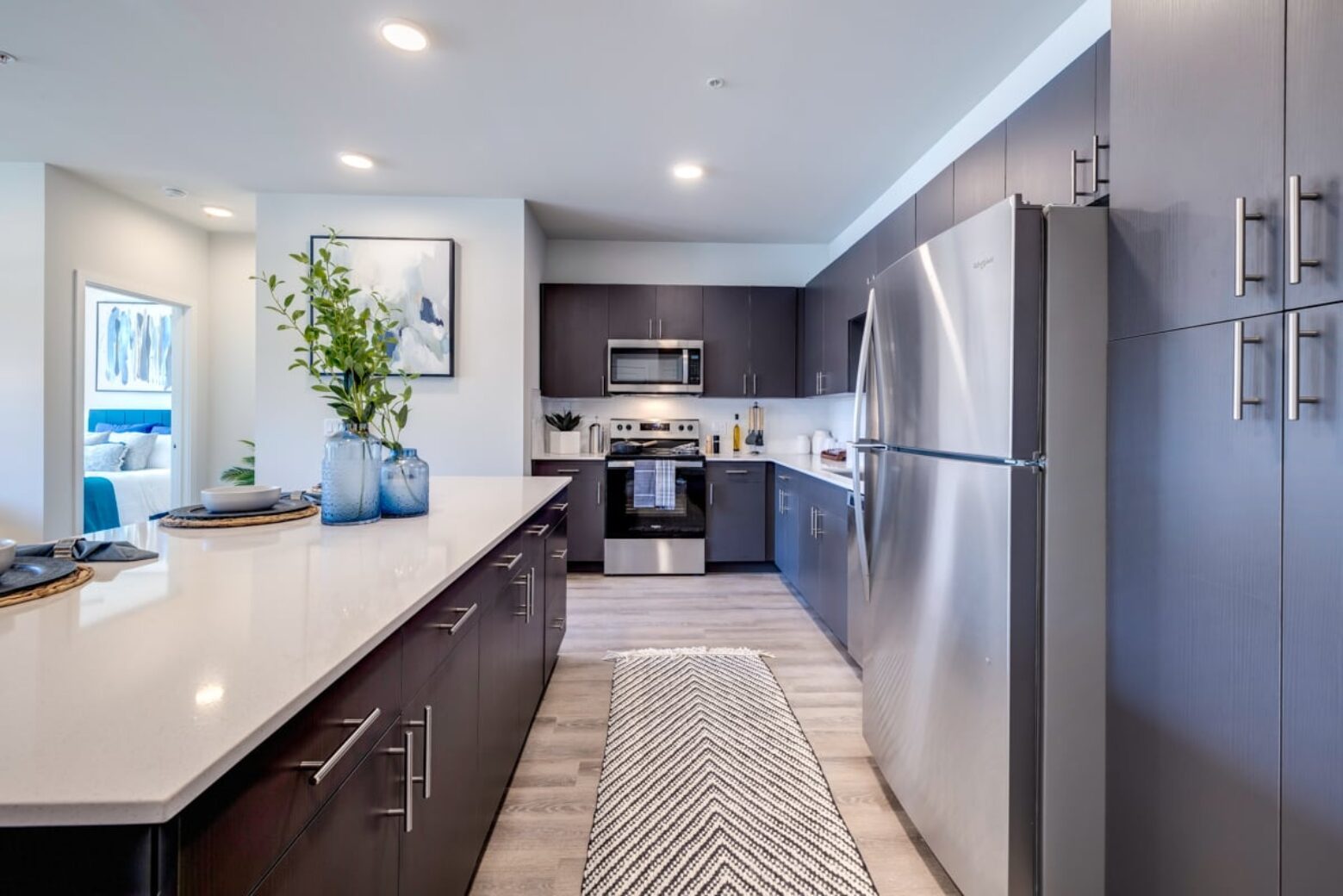 Modern apartment kitchen in Puyallup with stainless steel appliances, dark cabinets, and a white countertop.